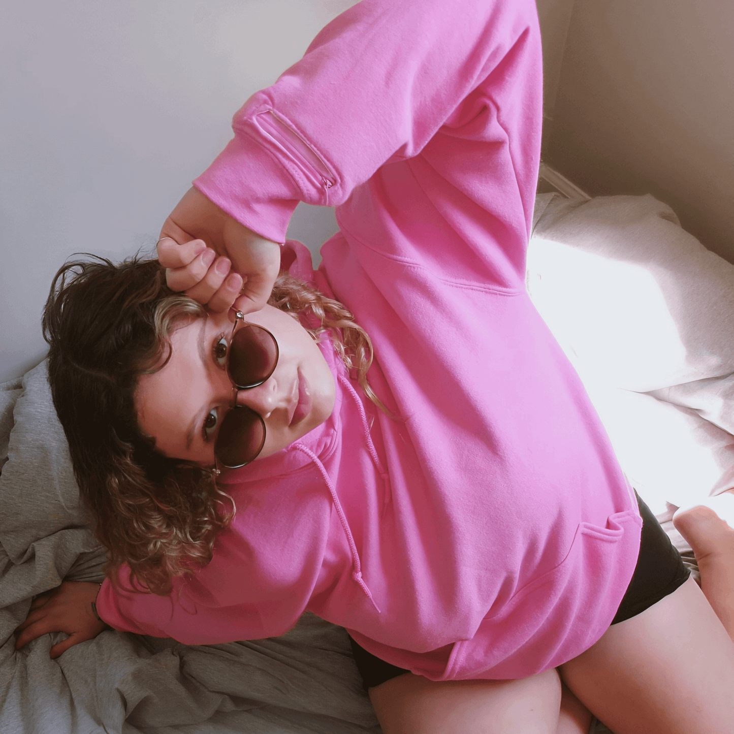 A contemplative individual wearing a soft pink Azalea brand comfort hoodie, artfully designed for aromatherapy and mental well-being. This essential oil-infused garment offers gentle anxiety relief, providing a serene escape through its subtle, calming scent, enriching personal scenes and promoting deep relaxation like a wearable perfume