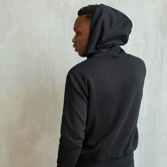 Modern man in a black Azalea brand hoodie, viewed from the back, showcasing its minimalist design and supreme comfort. Infused with essential oils, this comfort hoodie offers a discreet yet noticeable scent, elevating personal style and enriching urban scenes like a signature perfume.