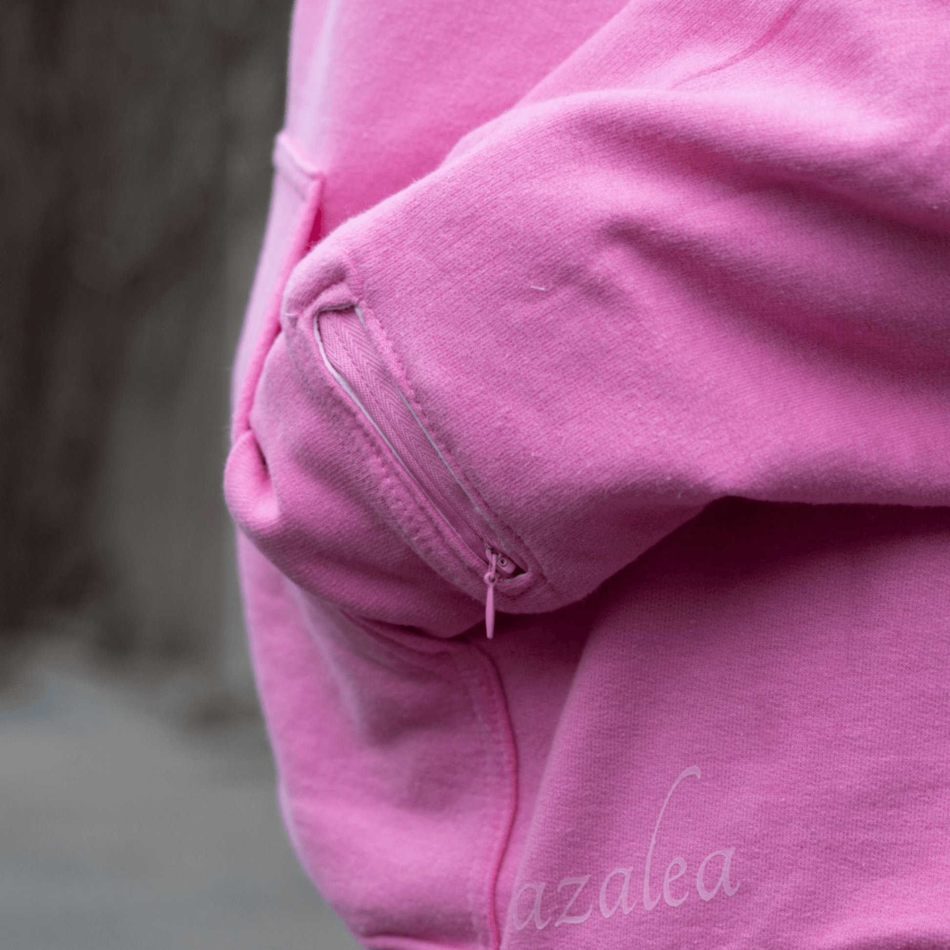 Detail of a pink hoodie sleeve, highlighting the discreet zipper pocket designed for essential oil aromatherapy